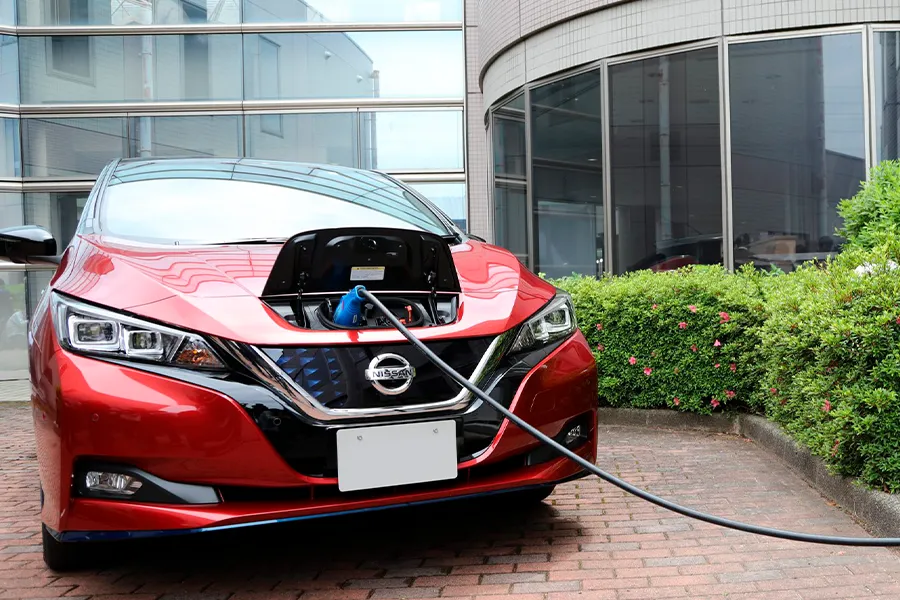 Mecânico inspeciona o compartimento do motor de um carro moderno em oficina, representando cuidados antes da compra de um veículo híbrido.